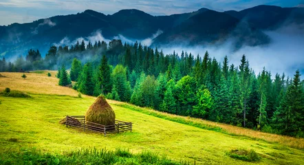 Fotobehang Amazing mountain landscape with fog and a haystack © seqoya