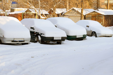 Cars under snow in residential yard in Russia