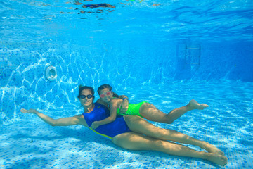 Mother and daughter dive in the swimming pool