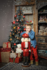 Christmas boy and the Nutcracker around Christmas tree with gift