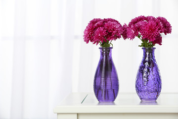 Beautiful bouquet of flowers in vases on window background