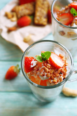 Healthy layered dessert with muesli and strawberries on table
