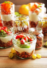 Healthy layered desserts with muesli and fruits on table