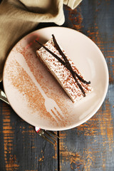 Tasty tiramisu cake on plate, on wooden table