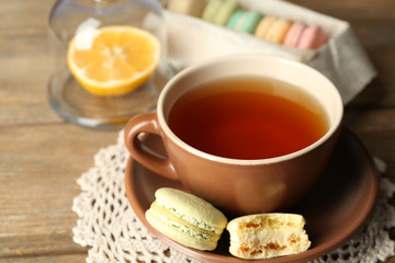 Colorful macaroons with cup of tea on wooden background