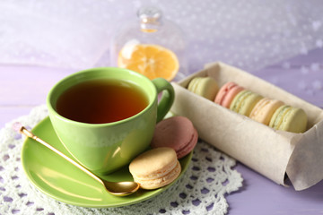Obraz na płótnie Canvas Colorful macaroons with cup of tea on wooden background