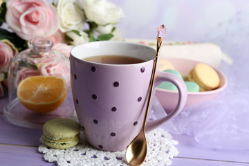 Colorful macaroons with cup of tea on wooden background