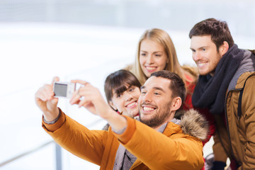 happy friends with camera on skating rink