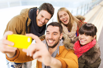 Obraz premium happy friends with smartphone on skating rink