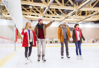 happy friends pointing finger on skating rink