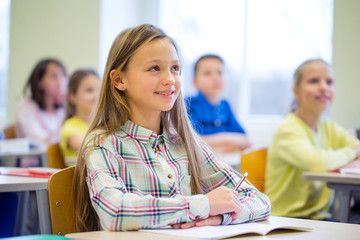 group of school kids with notebooks in classroom