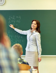school kids and teacher writing on chalkboard