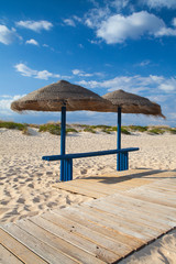 Different parasols and sun loungers on the empty beach on Tavira