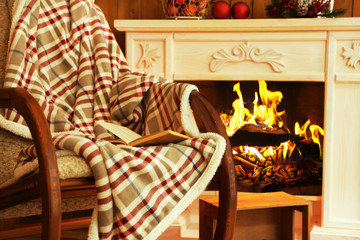 Rocking chair with plaid near fireplace