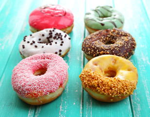 Delicious donuts with glaze on colorful wooden background