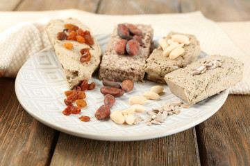 Assortment of sunflower halva on plate, on wooden background
