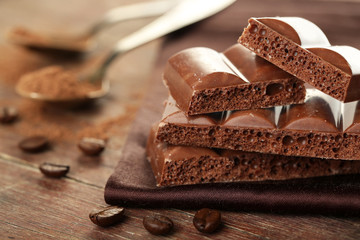 Tasty porous chocolate with cocoa beans, on wooden table