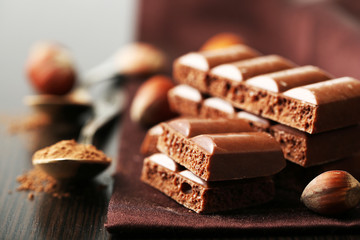 Tasty porous chocolate with nuts on table, close up