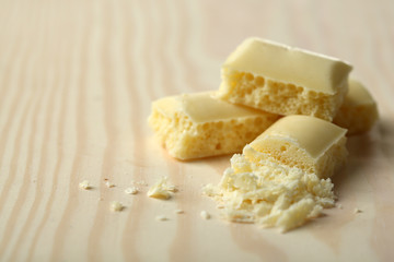 Tasty white porous chocolate on wooden table, close up