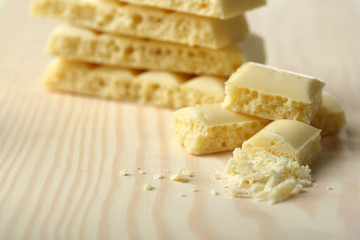 Tasty white porous chocolate on wooden table, close up