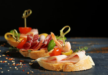 Tasty sandwiches on wooden table, on black background
