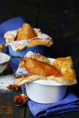 Small pear pies in cups, on wooden table