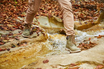 Hiker woman crossing a river, view of legs