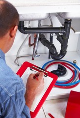 Plumber hands writing on clipboard.