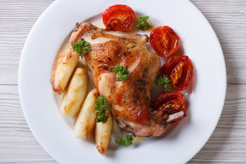roasted rabbit leg with apples and tomatoes on plate top view