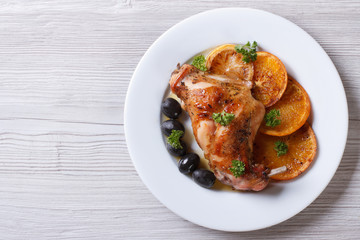 roasted rabbit leg with oranges on a white plate top view