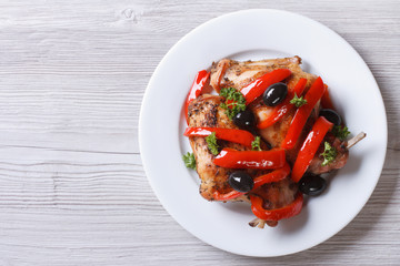 Roasted rabbit leg with peppers and olives top view horizontal