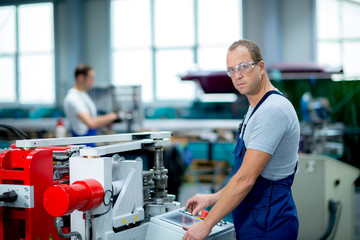 young worker in factory using machine