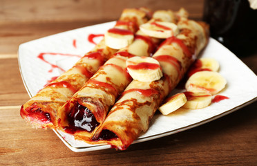 Plate of delicious pancakes with berry jam on wooden background