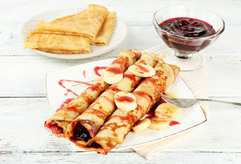 Plate of delicious pancakes with berry jam on wooden background
