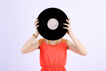 Young woman holding retro record in front of face,