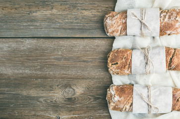 Obraz na płótnie Canvas Freshly baked rustic village bread (baguette) set on rough wood