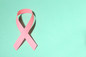 Pink breast cancer ribbon on turquoise background