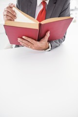 Businessman sitting at desk reading book