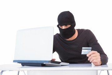 Burglar doing online shopping with laptop and credit card