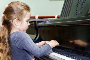 Cute little girl playing grand piano