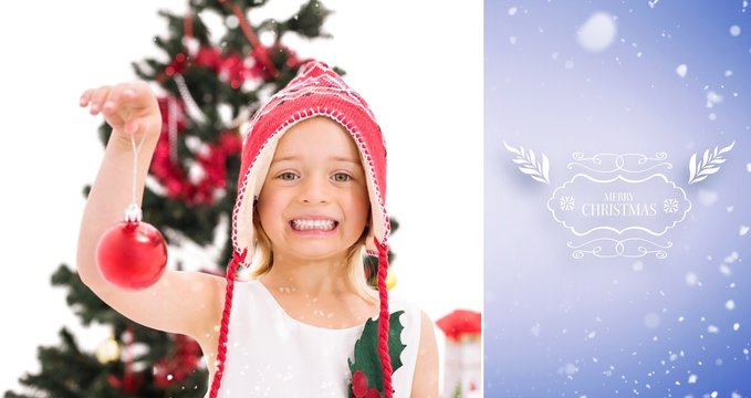 Composite image of festive little girl holding christmas bauble