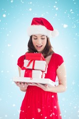 Composite image of festive brunette holding gifts