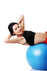 Fototapeta na wymiar Side view of a woman exercising on fitness ball
