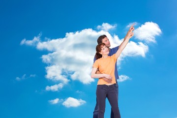 Composite image of happy couple pointing upwards together