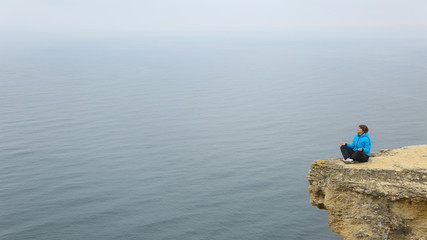 Fototapeta na wymiar beautiful woman meditating on a rock above the sea