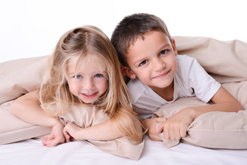 two little children brother and sister playing together in bed