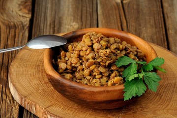 Cooked lentils in wooden bowl witn metal spoon