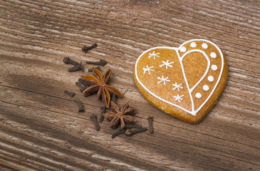 Gingerbread heart with spices on wooden background