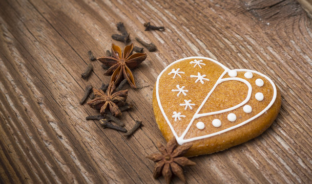 Gingerbread heart with spices on wooden background