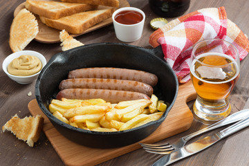 grilled sausages with French fries  in a frying pan, toasts